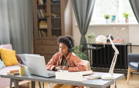 Adorable schoolboy in headphones listening to explanations of teacher