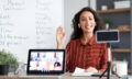 Smiling young woman teaching english to students online, waving hello